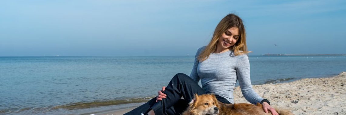 Woman enjoying a sunny day at Kołobrzeg beach with her dog, capturing a perfect seaside moment.