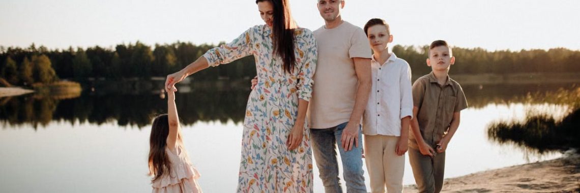 A family of five enjoys a serene lakeside vacation at sunset, capturing precious moments together.